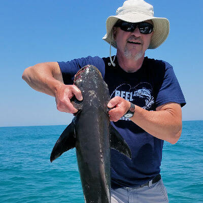 Beautiful day with angler holding up large inshore caught Cobia for a picture.