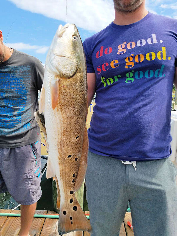 Anglre holding Red Drum with multiple round spots on tail.