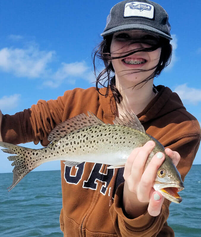 Young Sadie holds small Speckled Trout caught on light tackle.