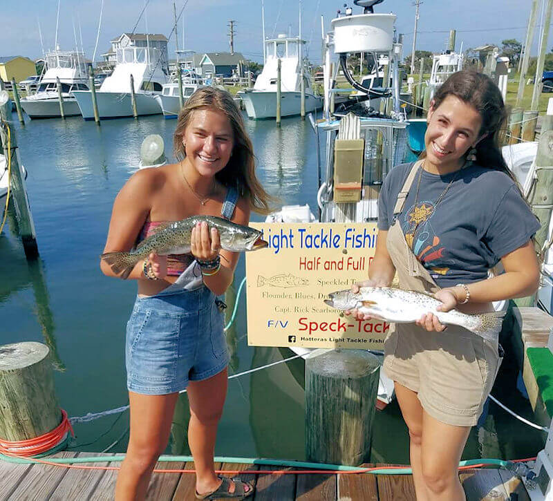 Young ladys holding up speckled trout for a picture.