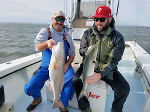 Two anglers holding nice fish caught on an inshore fishing charter.